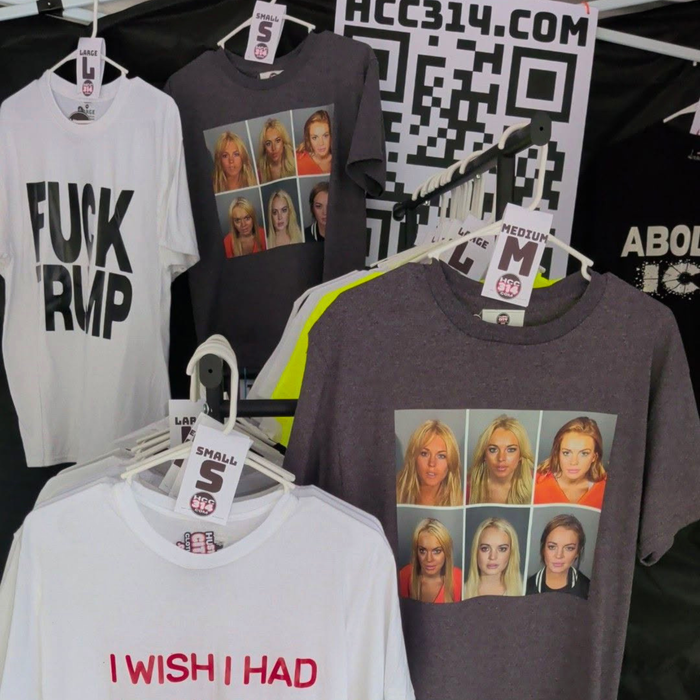 Apparel and accessories displayed inside a Hustle City Clothing vendor booth at a public market event