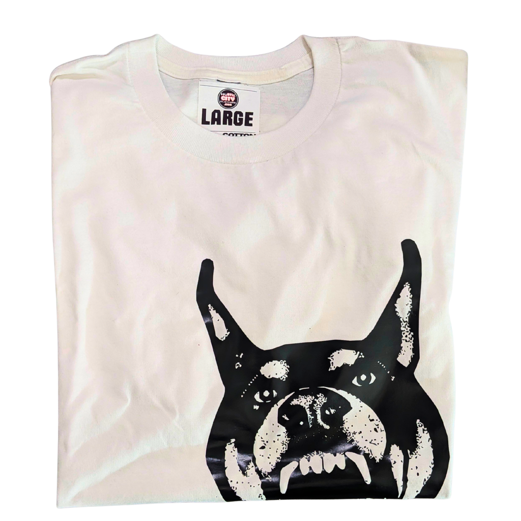 Folded t-shirt with a black and white dog graphic on a beige background