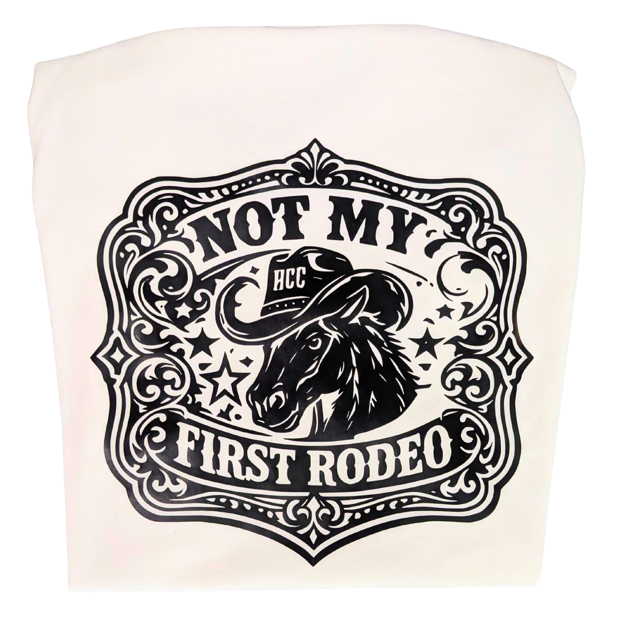 An off-white fabric item, likely a tote bag or pouch, featuring a black western-themed graphic print with a horse illustration and the text 'NOT MY FIRST RODEO' and 'HCC'.