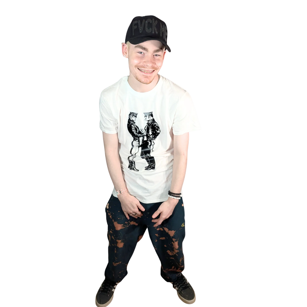 Person wearing a white t-shirt with graphic design, black cap, and dark jeans on a white background