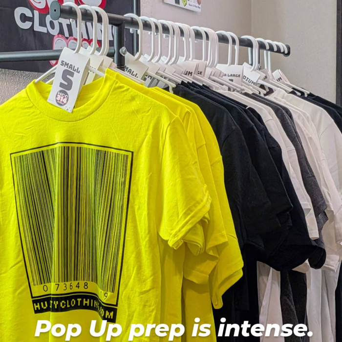 Apparel organized on a garment rack during event setup and inventory preparation.