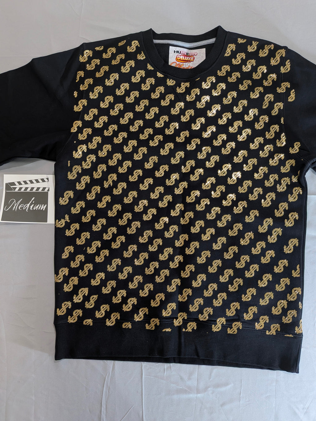 Black sweater with gold dollar sign pattern on a white background
