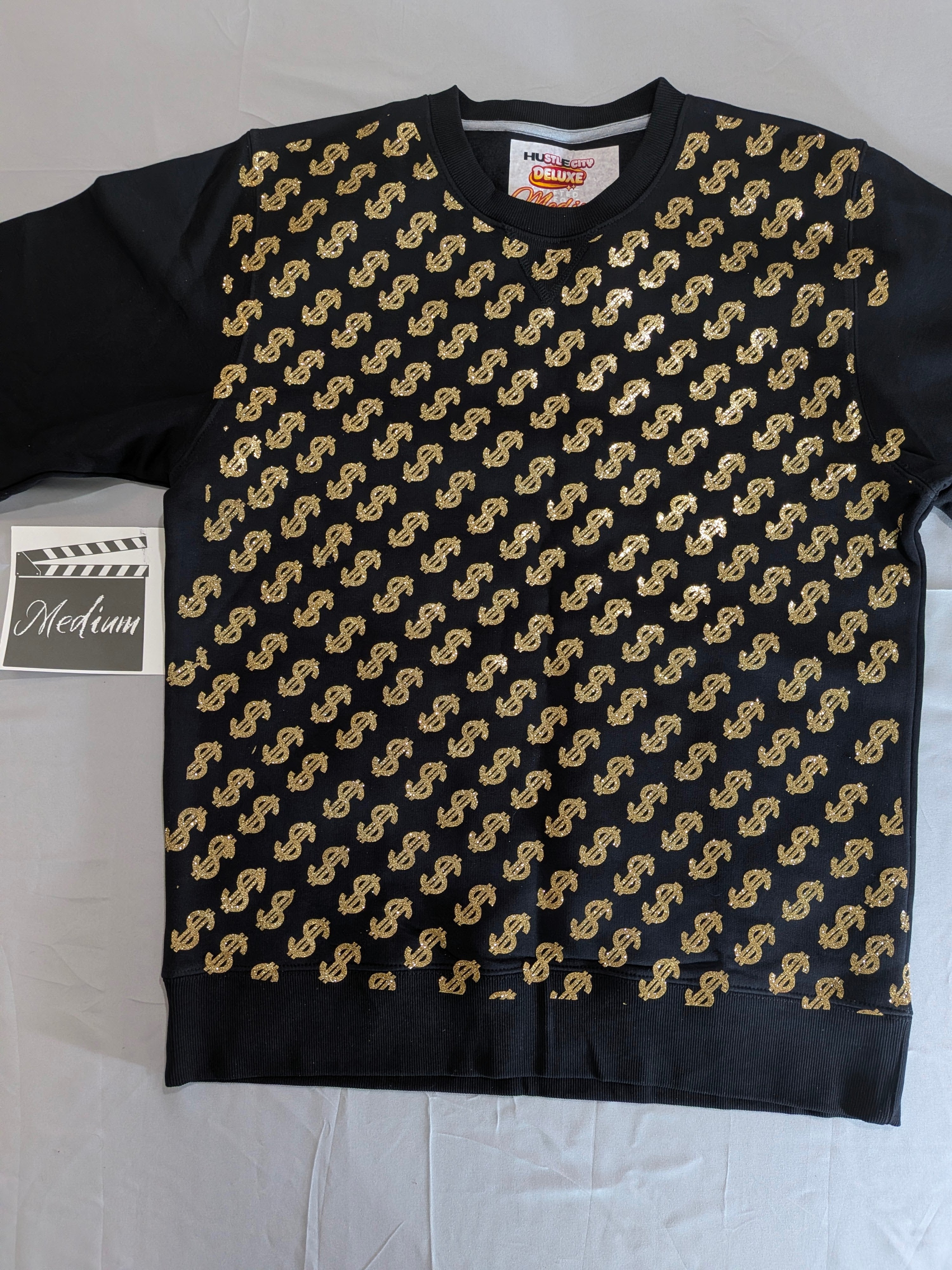 Black sweater with gold dollar sign pattern on a white background